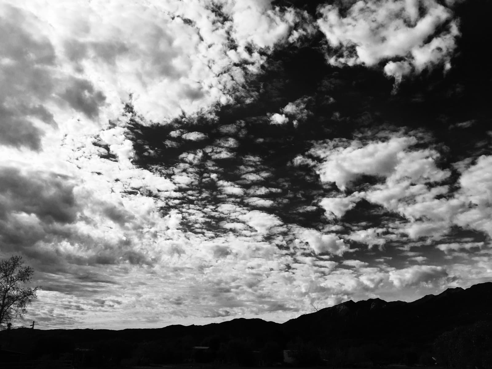 Black-and-white sky, banked clouds above a dark ridge line