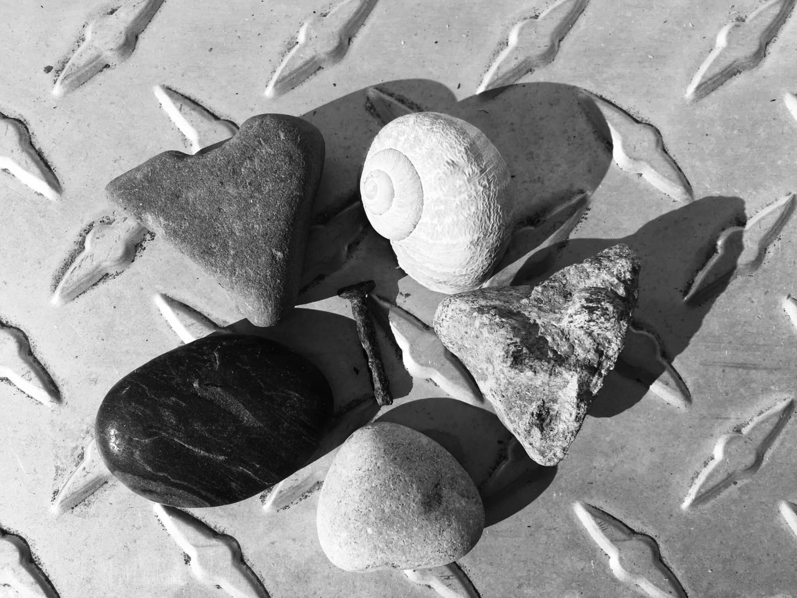 Smooth river stones arranged on a metal diamond-plate surface, black and white