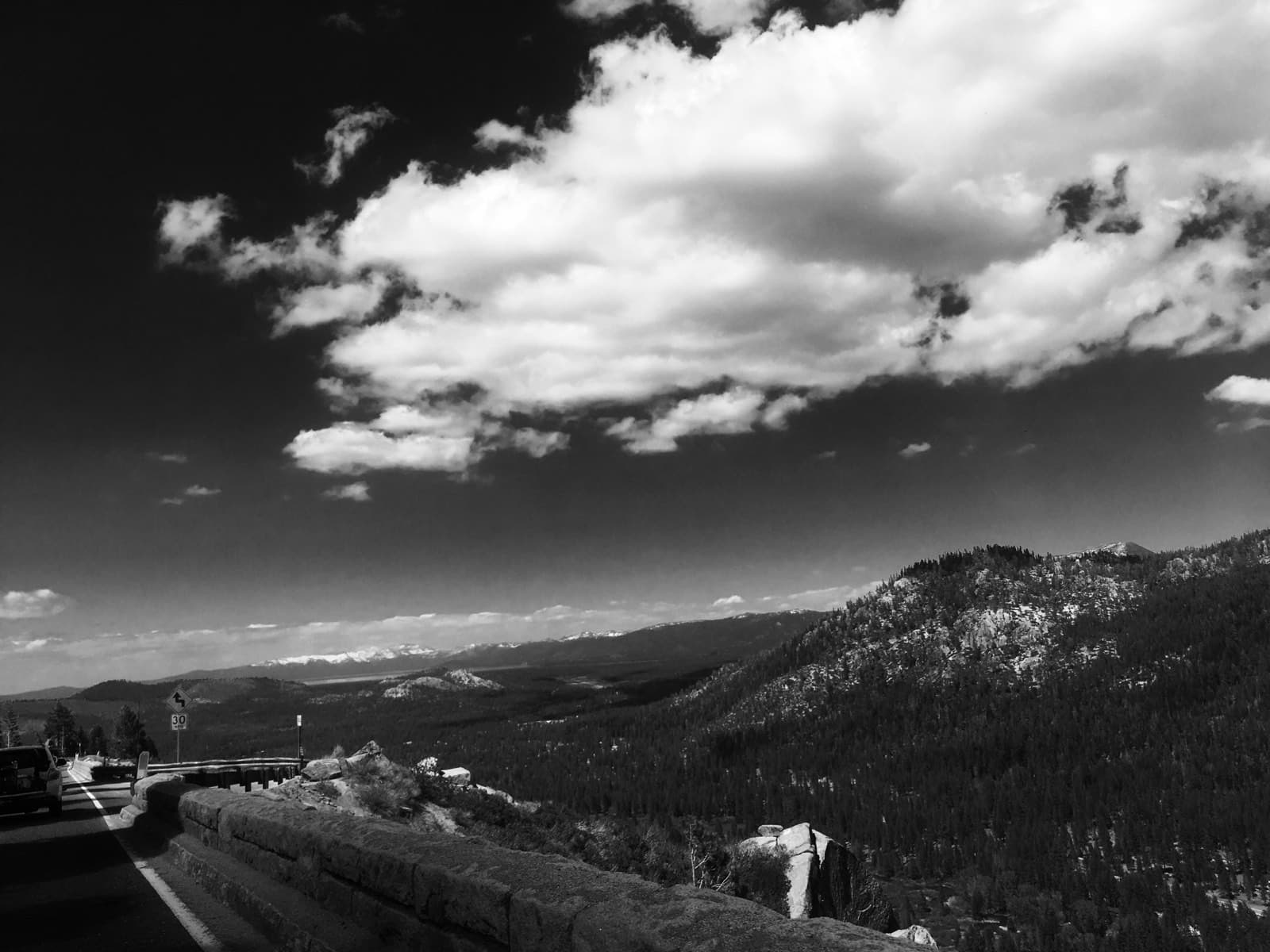 Black-and-white view down a valley road with cloud overhead