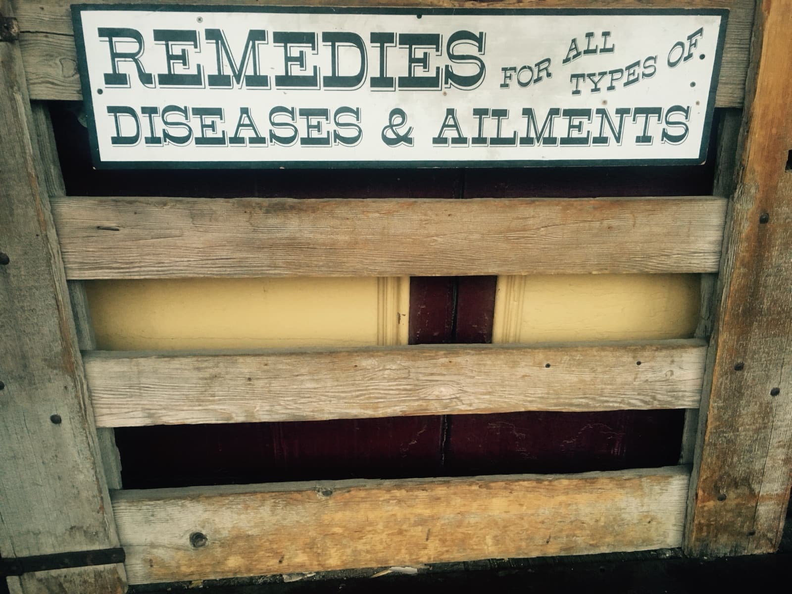 A painted sign reading Remedies for all types of diseases and ailments above weathered wooden slats